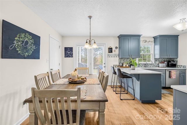 dining room with baseboards, light wood-style floors, a chandelier, and a textured ceiling