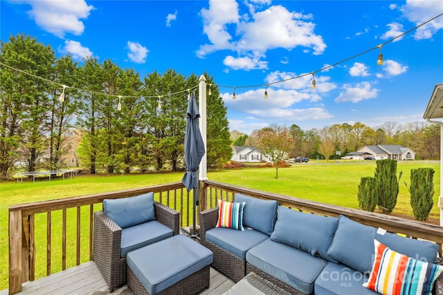 wooden deck featuring outdoor lounge area, a trampoline, and a yard