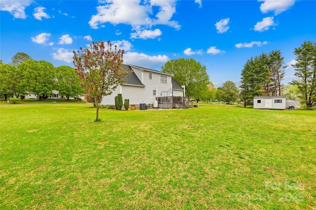 view of yard featuring an outdoor structure and central AC