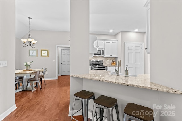 4159 Isle Of Pines Dr, Denver, NC 28037 - kitchen with stainless steel appliances, a sink, a breakfast bar, light wood-type flooring, and baseboards