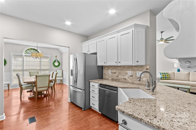 4159 Isle Of Pines Dr, Denver, NC 28037 - kitchen with stainless steel appliances, a sink, light stone counters, white cabinetry, and backsplash