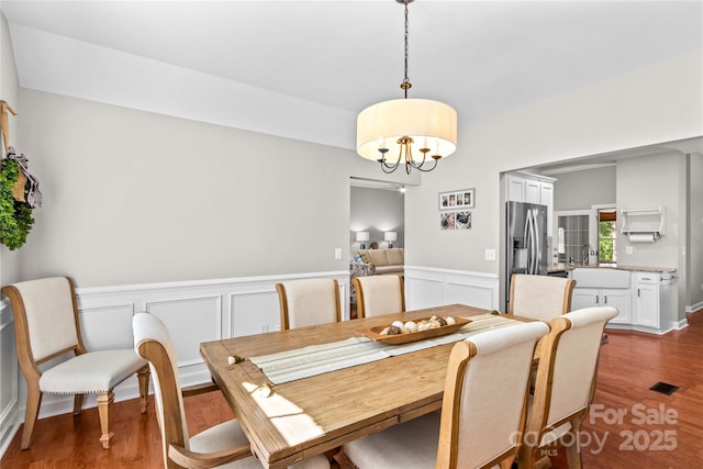 4159 Isle Of Pines Dr, Denver, NC 28037 - dining area with a chandelier, a decorative wall, wood finished floors, and wainscoting