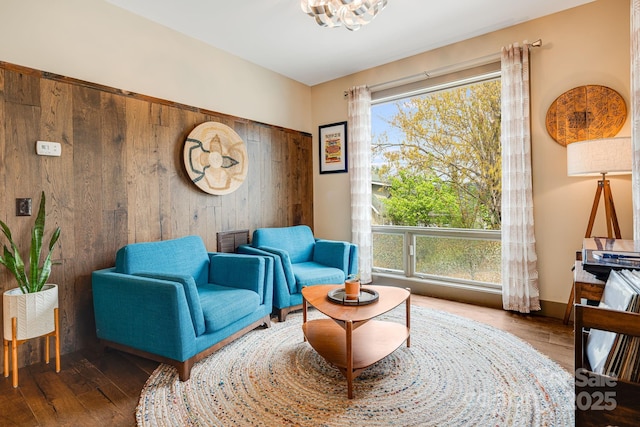 sitting room with wood-type flooring, plenty of natural light, and a notable chandelier