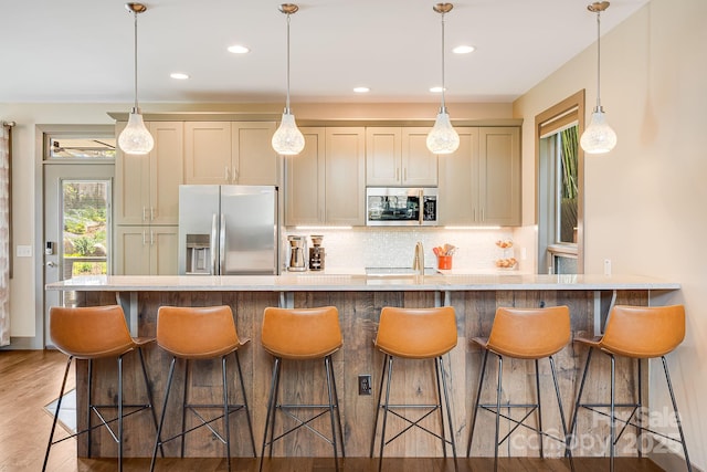 kitchen with decorative light fixtures, light wood-style floors, backsplash, and appliances with stainless steel finishes