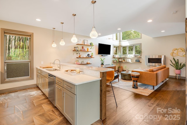kitchen with dishwasher, a sink, light countertops, a peninsula, and a kitchen bar
