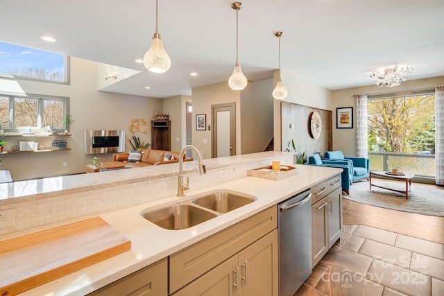 kitchen with open floor plan, dishwasher, a sink, and light countertops