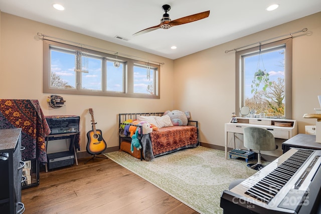 bedroom with visible vents, baseboards, multiple windows, and wood finished floors