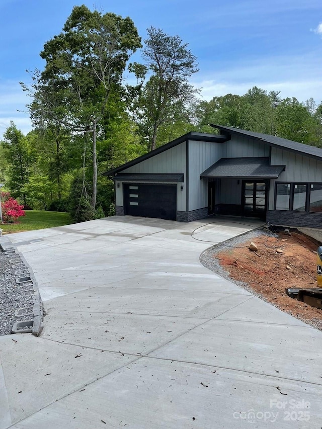 27 George Allen Rdg, Arden, NC 28704 - view of home's exterior with concrete driveway, a garage, board and batten siding, and view of wooded area