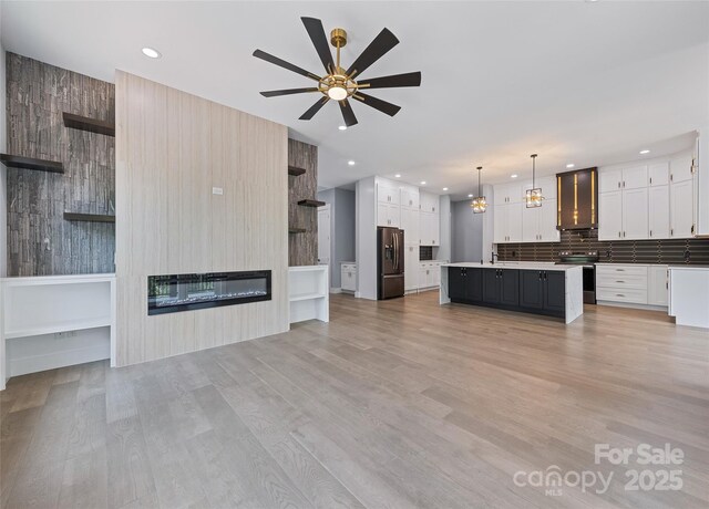 27 George Allen Rdg, Arden, NC 28704 - unfurnished living room featuring a fireplace, recessed lighting, a ceiling fan, light wood finished floors, and a chandelier