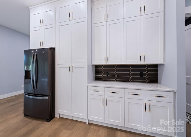 27 George Allen Rdg, Arden, NC 28704 - kitchen with black refrigerator with ice dispenser, light wood-style floors, white cabinetry, light stone counters, and tasteful backsplash