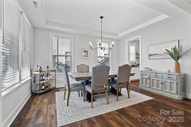 dining space with visible vents, baseboards, dark wood-type flooring, a tray ceiling, and an inviting chandelier