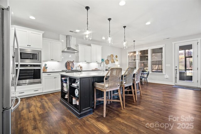 kitchen featuring decorative backsplash, appliances with stainless steel finishes, white cabinetry, open shelves, and wall chimney range hood