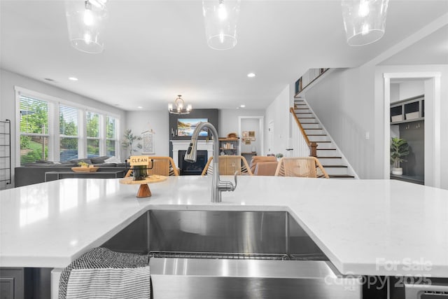 kitchen featuring a fireplace, recessed lighting, a sink, open floor plan, and hanging light fixtures