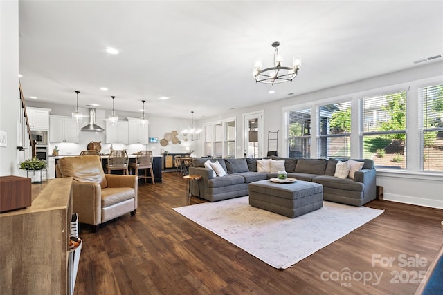 living room with dark wood-style flooring, visible vents, recessed lighting, and a notable chandelier