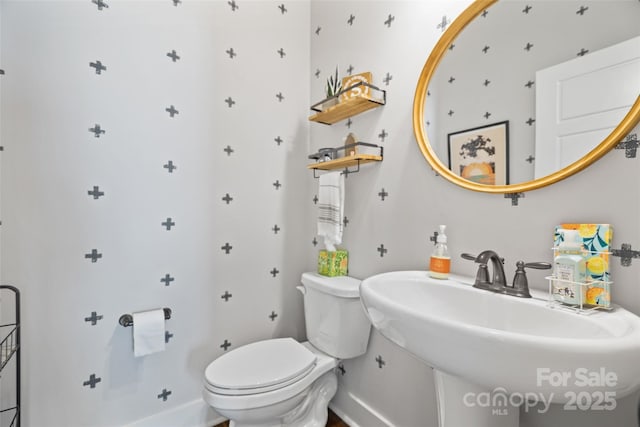 bathroom with baseboards, a sink, and toilet