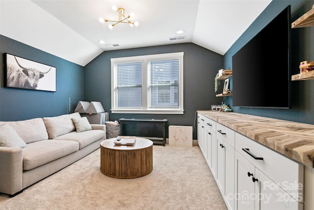 living area with light carpet, visible vents, an inviting chandelier, and vaulted ceiling