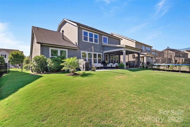 rear view of house with a trampoline, fence, outdoor lounge area, a patio, and a yard
