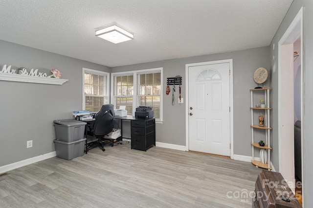 office with a textured ceiling, baseboards, and light wood-type flooring