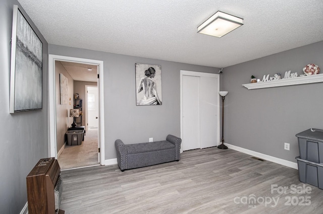 living area with a textured ceiling, baseboards, and wood finished floors