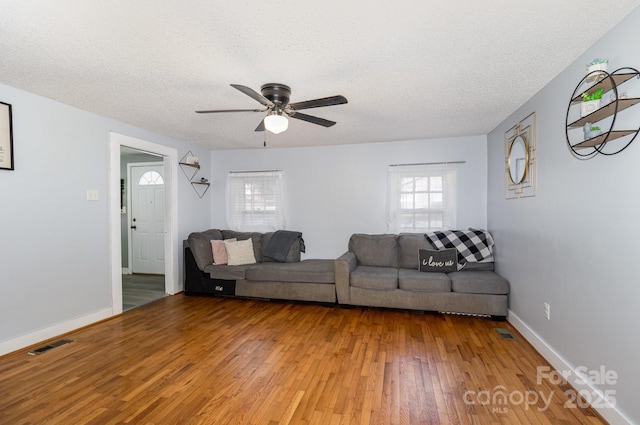 unfurnished living room featuring a ceiling fan, a textured ceiling, baseboards, and light wood-type flooring