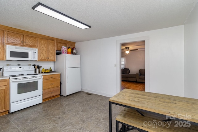 kitchen with a textured ceiling, light countertops, brown cabinets, and white appliances