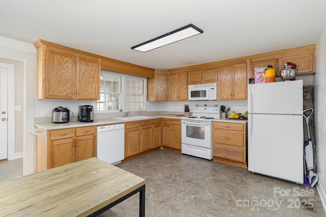 kitchen with white appliances, light countertops, a sink, and a textured ceiling