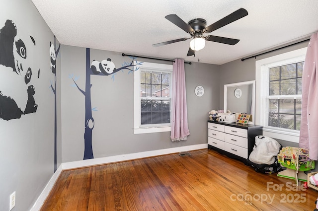 unfurnished bedroom featuring baseboards, wood finished floors, and a textured ceiling