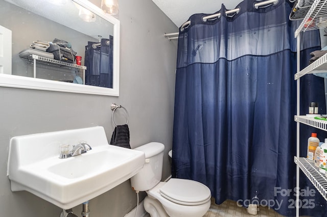 bathroom with a sink, toilet, tile patterned floors, and a shower with curtain