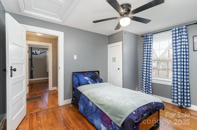 bedroom with baseboards, wood finished floors, ceiling fan, and a textured ceiling