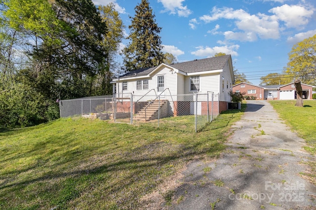 view of property exterior featuring a lawn, driveway, a shingled roof, and fence