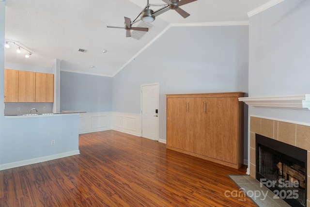 1000 Olde Eastwood Village Blvd Unit 307, Asheville, NC 28803 - unfurnished living room featuring vaulted ceiling, a tile fireplace, a ceiling fan, dark wood-style floors, and ornamental molding