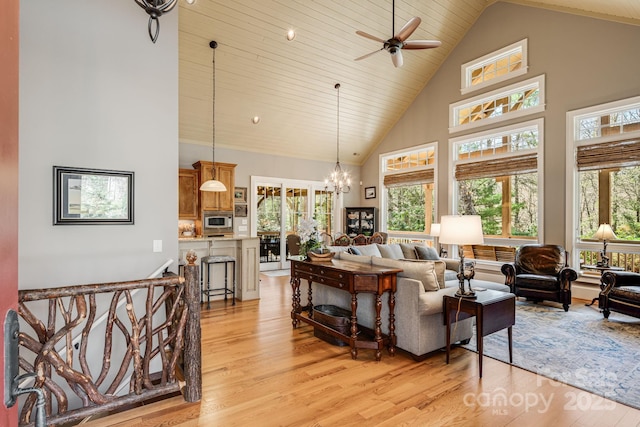 living room featuring high vaulted ceiling, ceiling fan with notable chandelier, light wood-style flooring, and a wealth of natural light