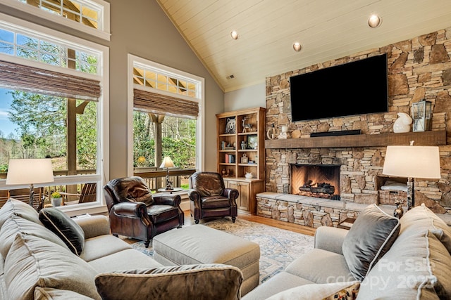 living area with high vaulted ceiling, wood finished floors, a wealth of natural light, and a fireplace