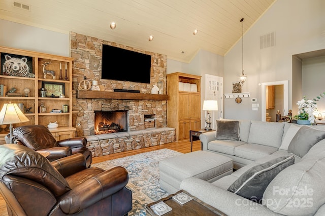 living area featuring high vaulted ceiling, a fireplace, wood finished floors, and visible vents