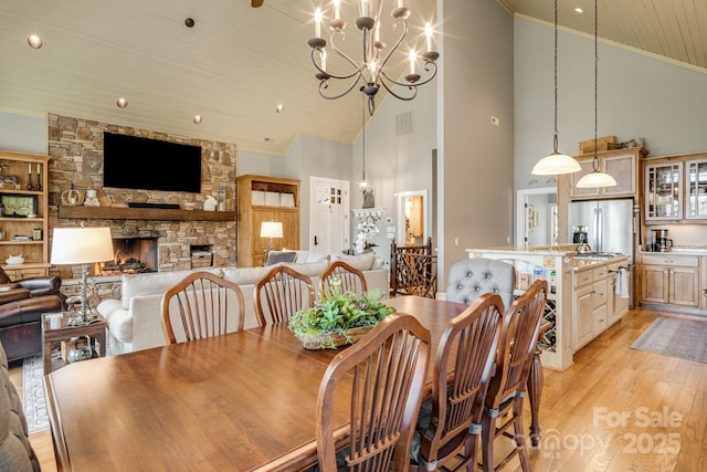 dining area featuring crown molding, light wood-style flooring, wooden ceiling, and an inviting chandelier