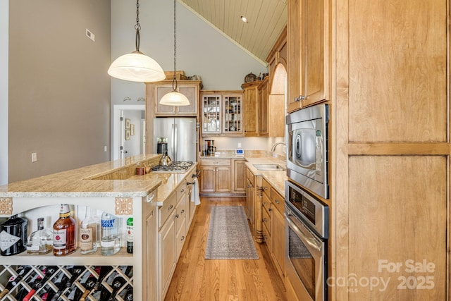 kitchen featuring appliances with stainless steel finishes, a sink, light wood finished floors, high vaulted ceiling, and wood ceiling
