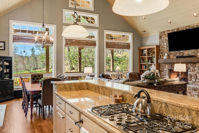 kitchen featuring light wood finished floors, stainless steel gas cooktop, wood ceiling, and high vaulted ceiling