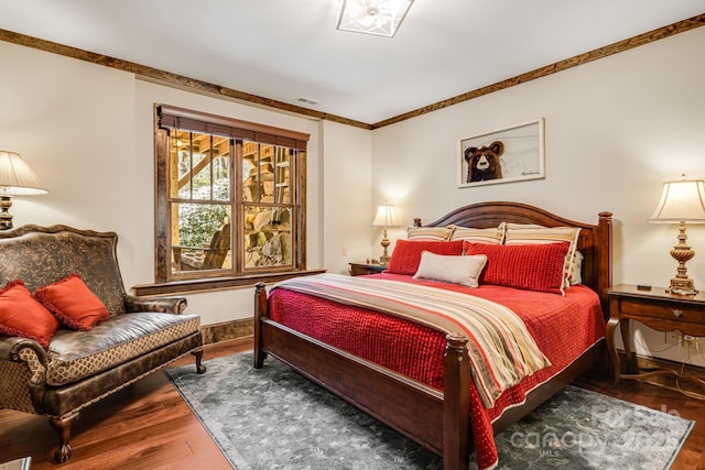 bedroom featuring baseboards, ornamental molding, wood finished floors, and visible vents