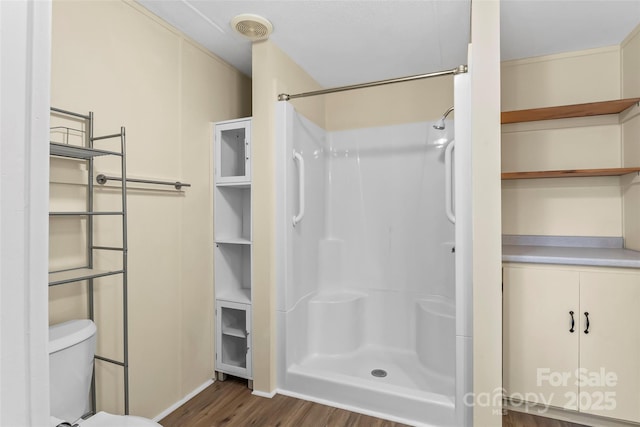 bathroom featuring wood finished floors, visible vents, toilet, and walk in shower