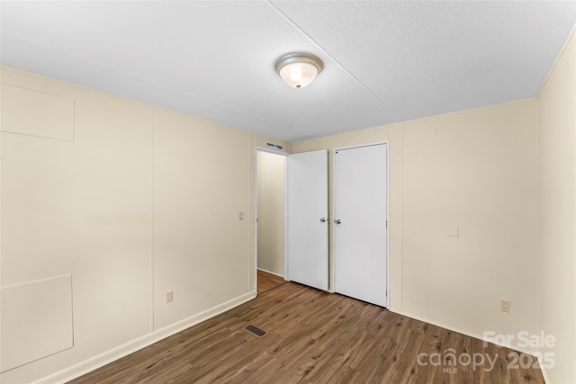 unfurnished bedroom with visible vents, a closet, and wood finished floors
