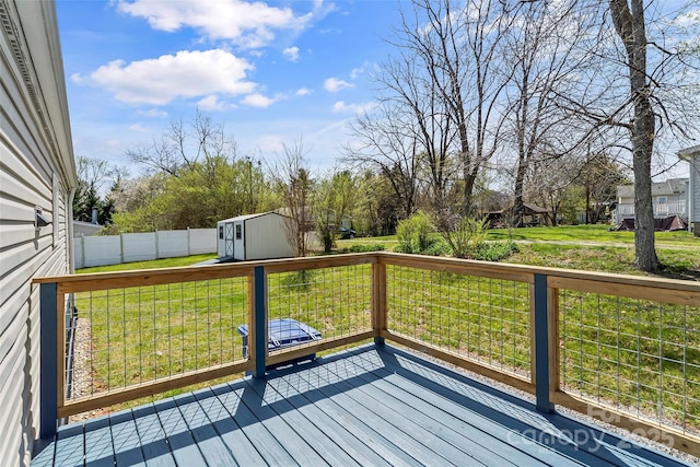 wooden deck featuring fence, an outdoor structure, a yard, and a shed