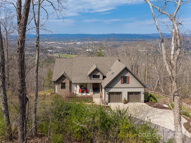 view of front of house featuring roof with shingles, board and batten siding, driveway, a mountain view, and a garage