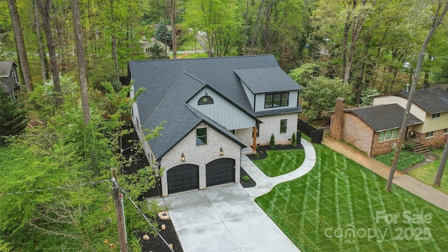 view of front of property with a front yard, concrete driveway, roof with shingles, board and batten siding, and a garage