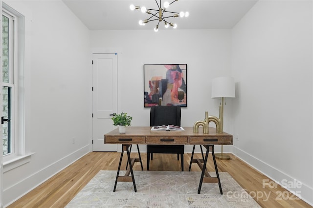 office featuring baseboards, a notable chandelier, and light wood-type flooring