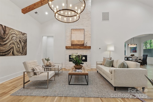 living room with beam ceiling, wood finished floors, visible vents, arched walkways, and an inviting chandelier