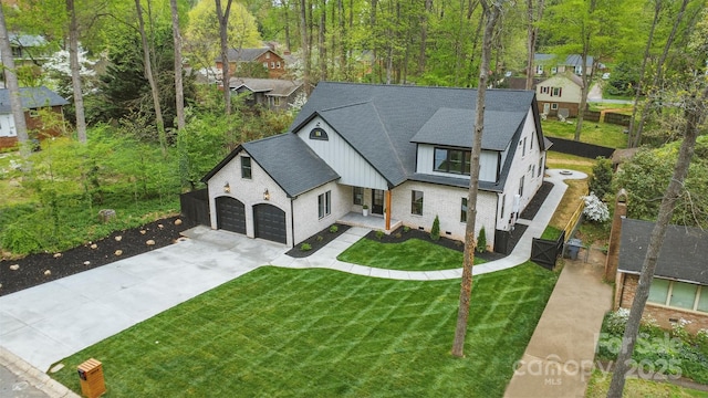 view of front of house featuring concrete driveway, an attached garage, board and batten siding, a front yard, and a shingled roof