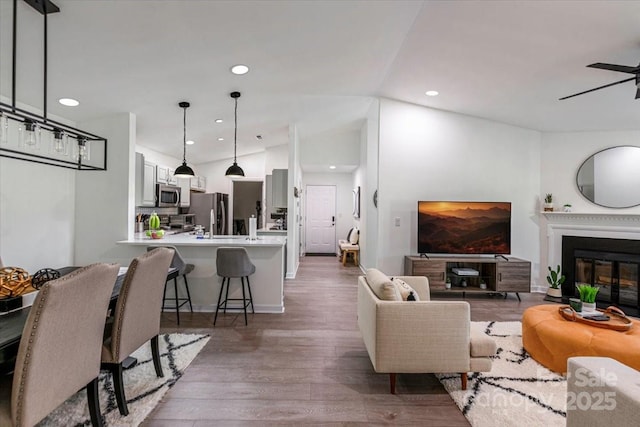 17143 Red Feather Dr, Charlotte, NC 28277 - living room featuring wood finished floors, recessed lighting, a ceiling fan, lofted ceiling, and a glass covered fireplace