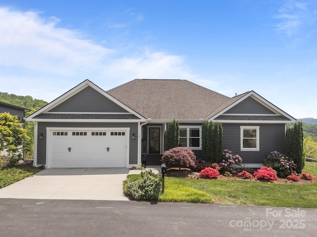 craftsman inspired home featuring a garage, a shingled roof, driveway, and a front lawn