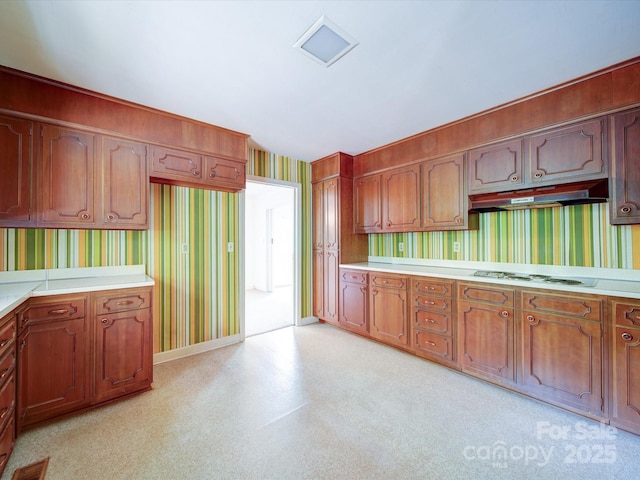 167 Cedar Ln, Troutman, NC 28166 - kitchen with wallpapered walls, under cabinet range hood, light countertops, and brown cabinets