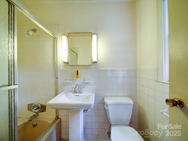 167 Cedar Ln, Troutman, NC 28166 - bathroom featuring toilet, tile walls, bath / shower combo with glass door, and wainscoting